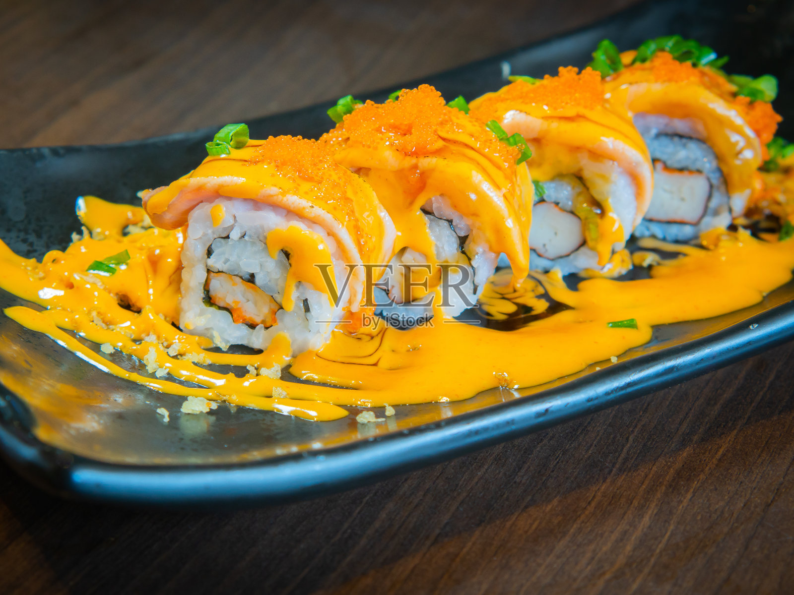 三文鱼烤卷上撒上辣味芝士酱。照片摄影图片