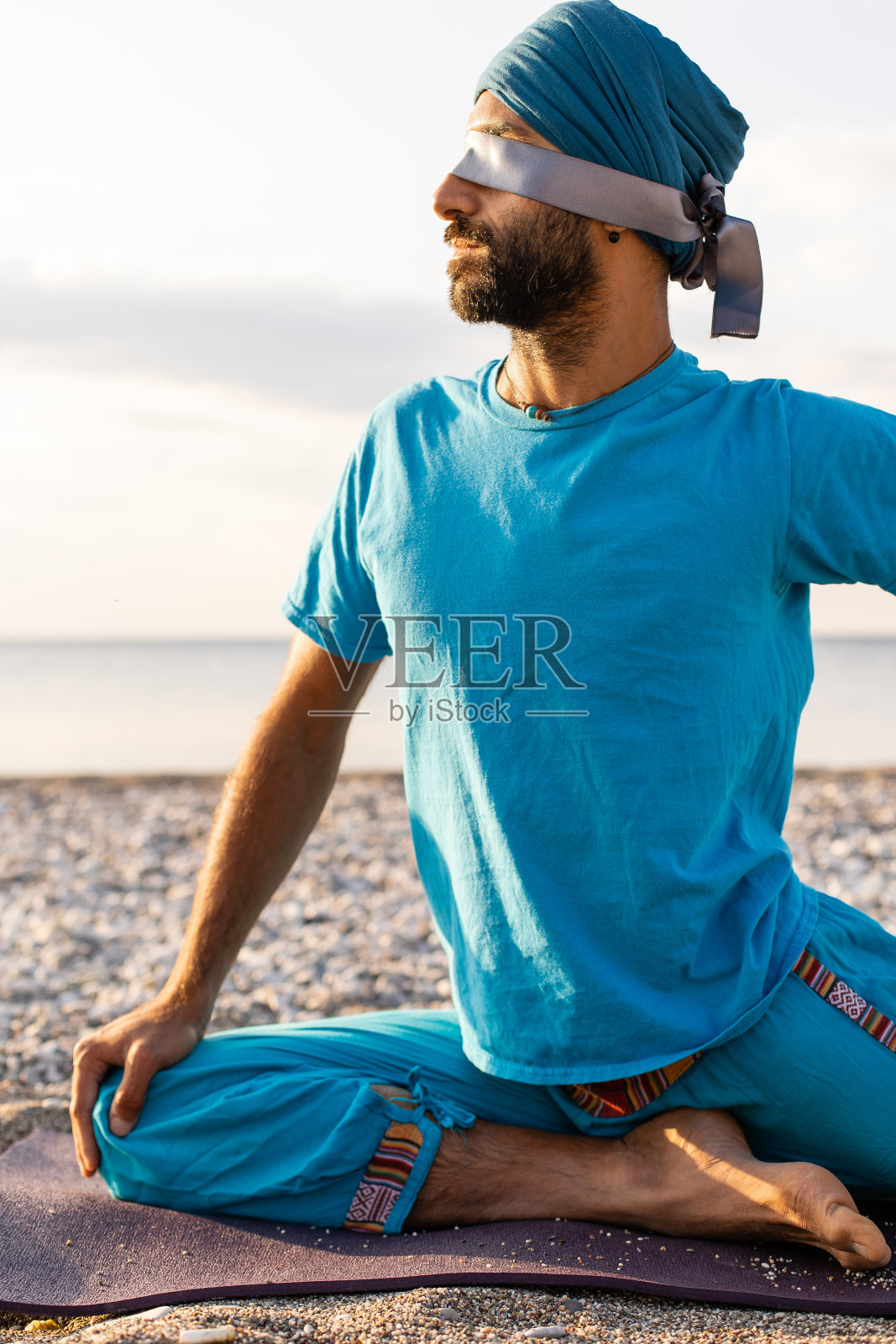 在日出或日落的时候，健康的年轻人在平静的海边练习瑜伽照片摄影图片