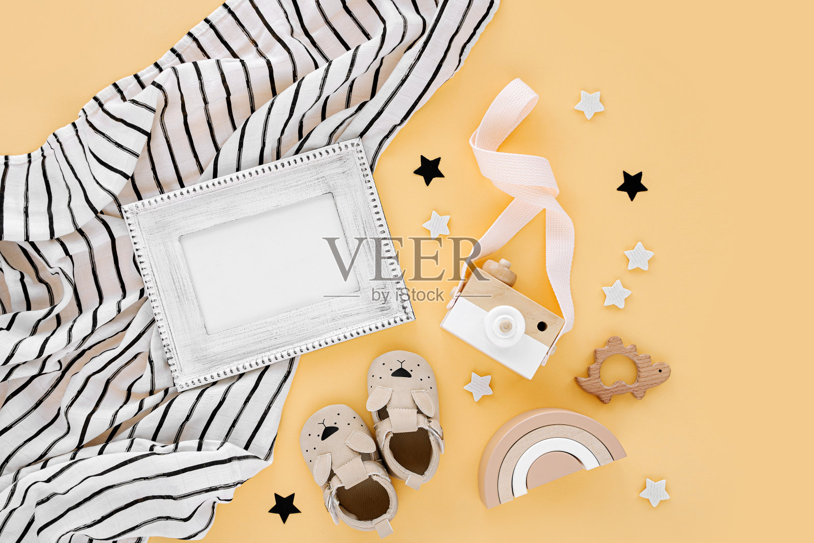 黑白细布襁褓与相框和婴儿拖鞋，玩具在黄色的背景。一套中性新生儿配件。平铺，俯视图照片摄影图片