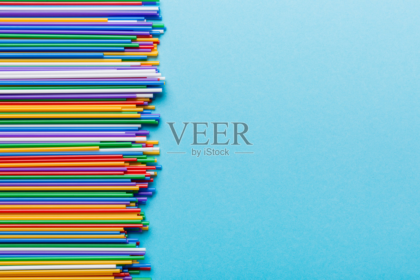 彩色背景上的彩色塑料吸管堆，平放。复制文本空间照片摄影图片