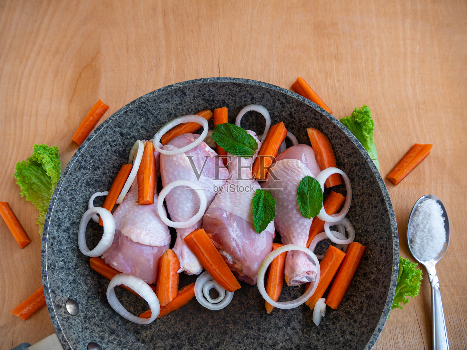 鸡腿与胡萝卜和绿色蔬菜在煎锅俯视图。肉类蔬菜香料烹饪。自制的美味的食物照片摄影图片