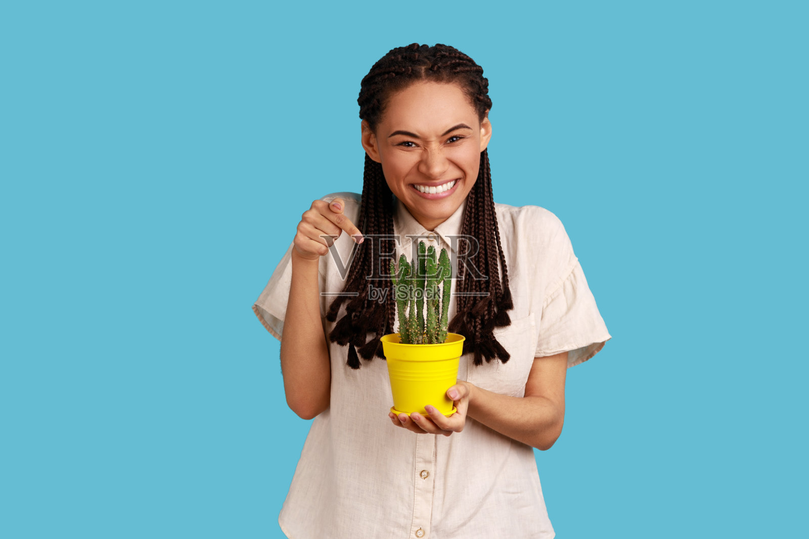 女人捧着一盆多汁的绿色仙人掌，微笑着，露出洁白的牙齿，多刺的花朵。照片摄影图片