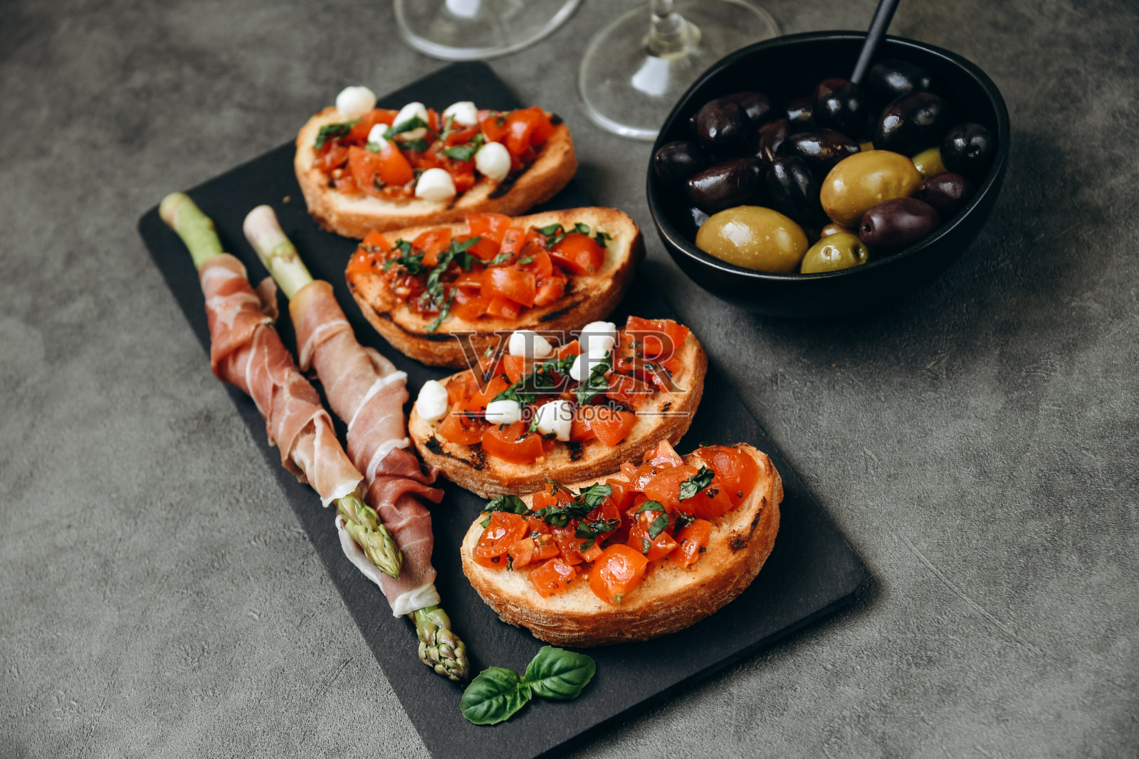 餐厅小吃烤面包配番茄芦笋配火腿和橄榄两杯白葡萄酒或普罗赛克照片摄影图片