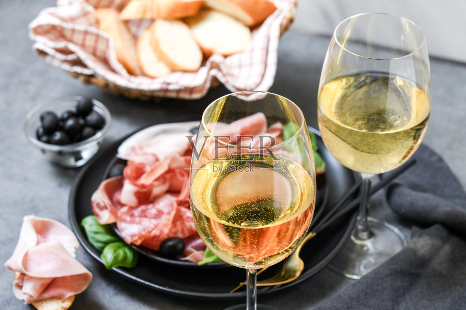 食物:意大利熏火腿，意大利腊肠，橄榄和面包条。熟食店。两杯白葡萄酒或普罗塞克葡萄酒照片摄影图片