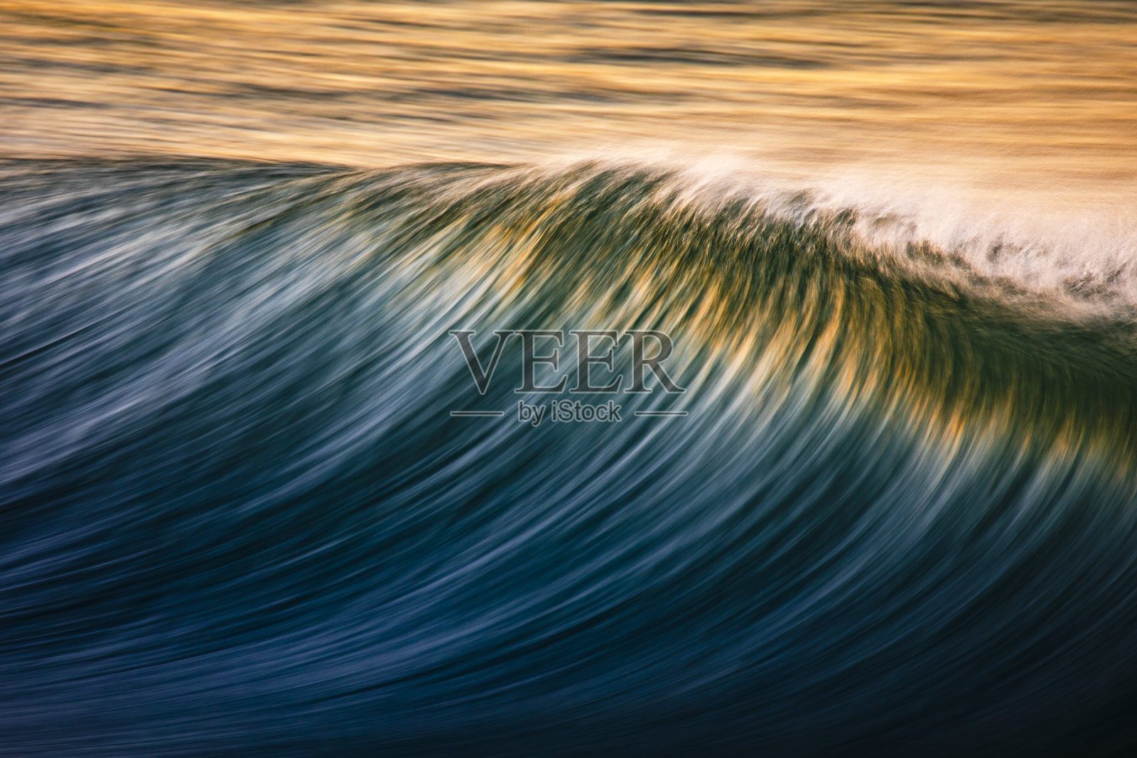 干净的海浪在海滩上反射出明亮的金色日出的特写照片摄影图片