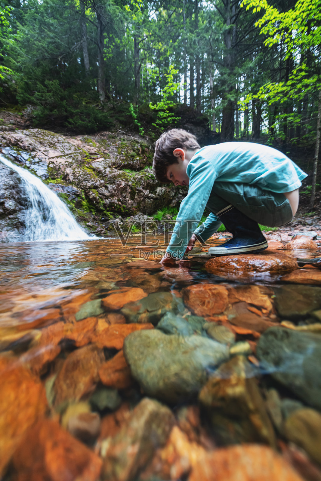 男孩在瀑布上玩耍照片摄影图片
