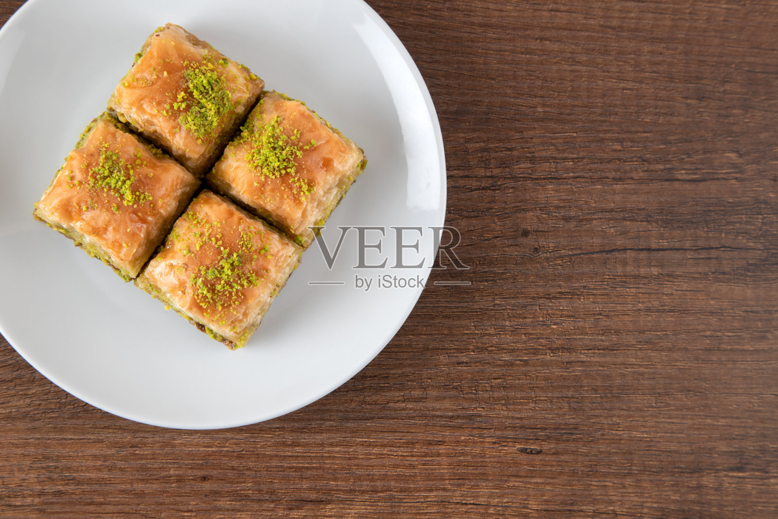 传统的开心果果仁蜜饼在白色盘子。木制背景的果仁蜜饼照片摄影图片