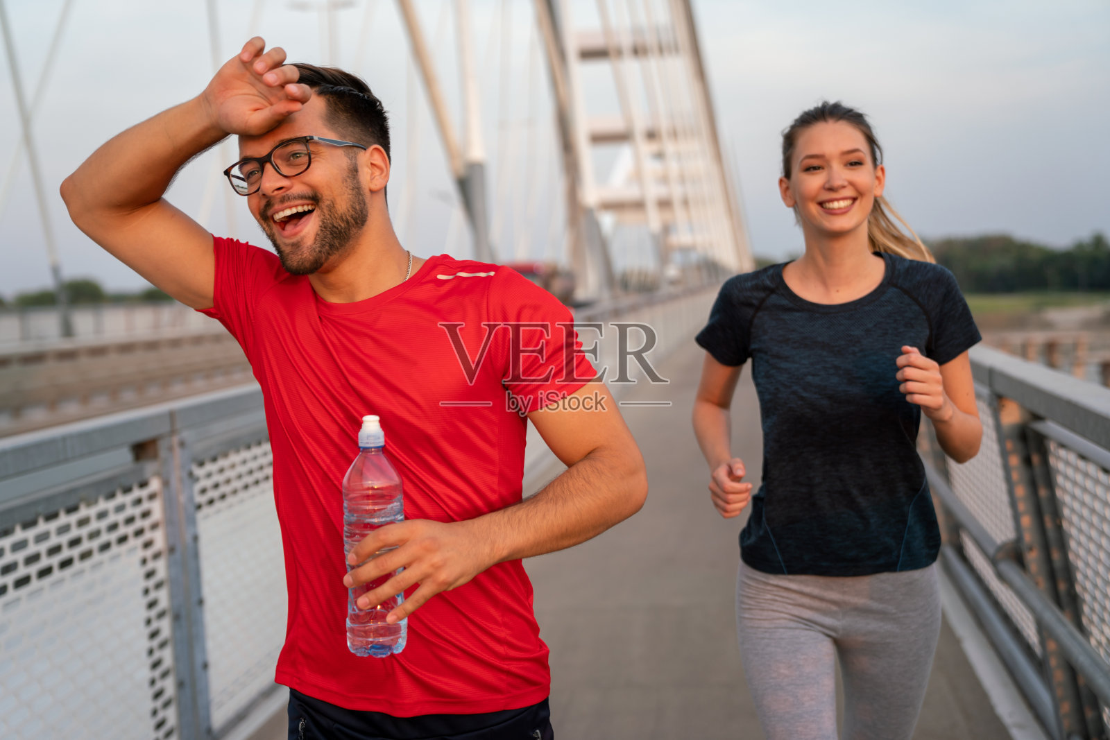 清晨锻炼。幸福的夫妇跑过桥。生活健康的生活方式。照片摄影图片