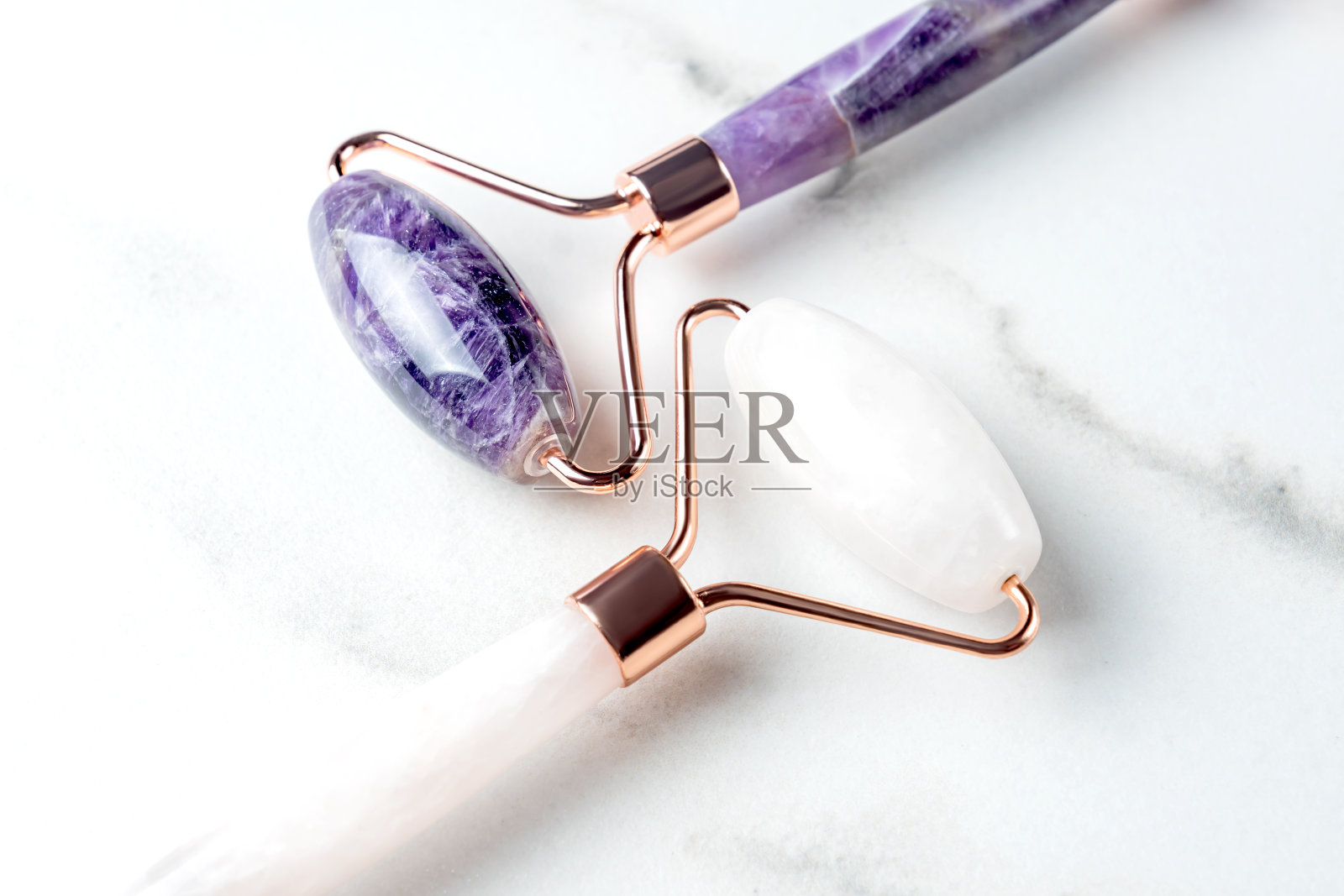 近距离按摩石英辊为粉红色的脸自然肾炎和紫水晶。刮痧按摩工具。抗年龄和举重在家里。皮肤护理面部按摩和放松的概念。照片摄影图片