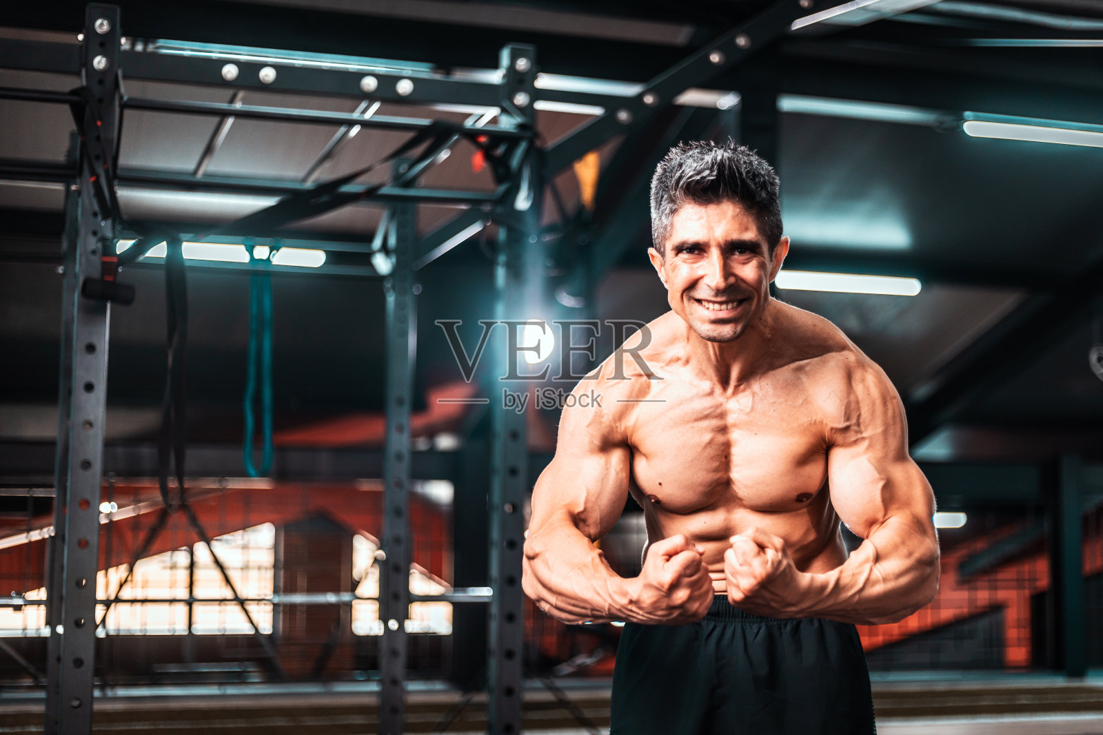 拥有完美体格的健美运动员，展示他的肱二头肌、腹肌和胸肌。一个躯干赤裸的肌肉男。经典的健美。照片摄影图片