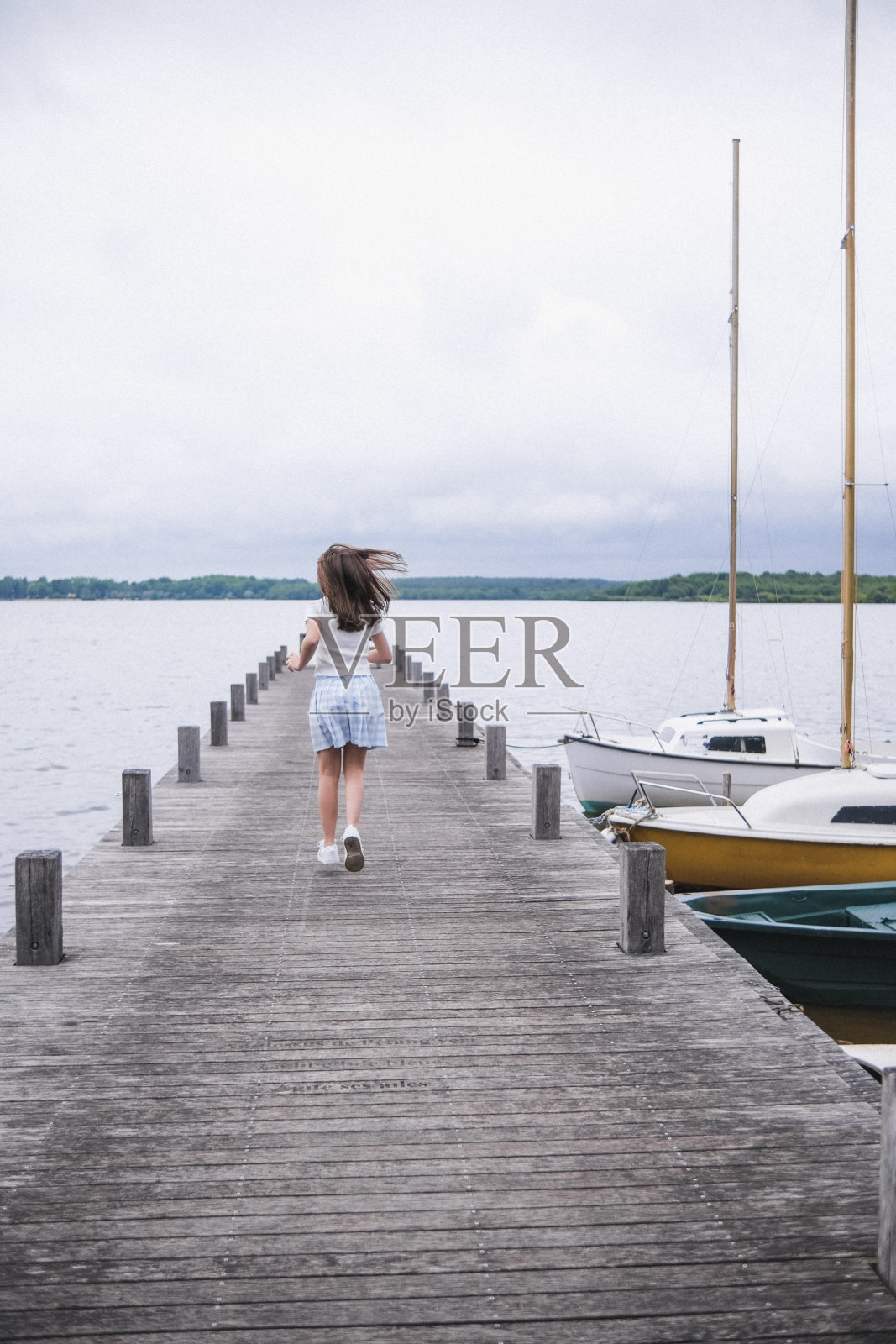 一个女孩跑在湖边的防波堤尽头照片摄影图片