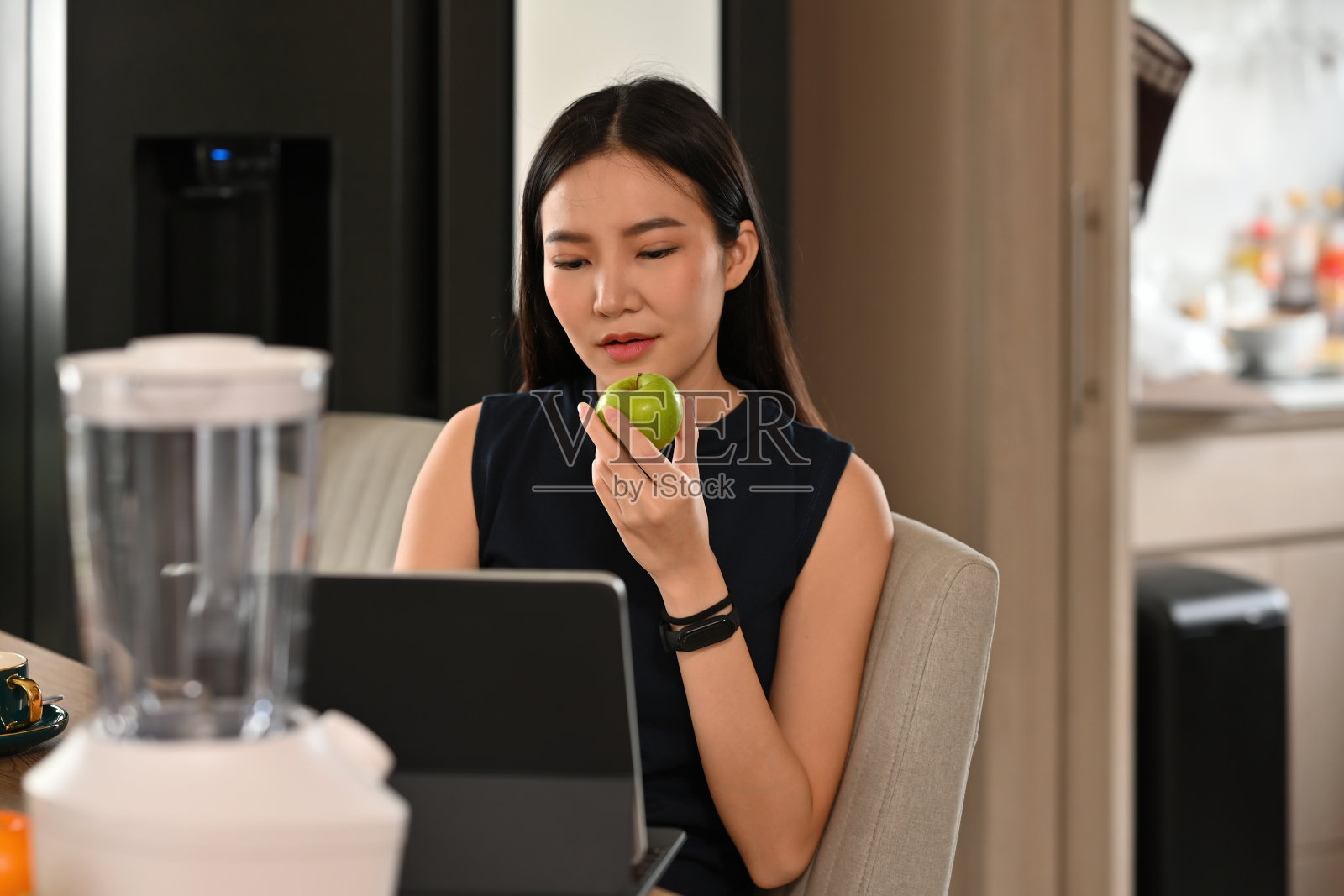 一个年轻漂亮的亚洲女人的肖像拿着一个苹果平板电脑看一个食谱，食物，健康和烹饪的概念。照片摄影图片