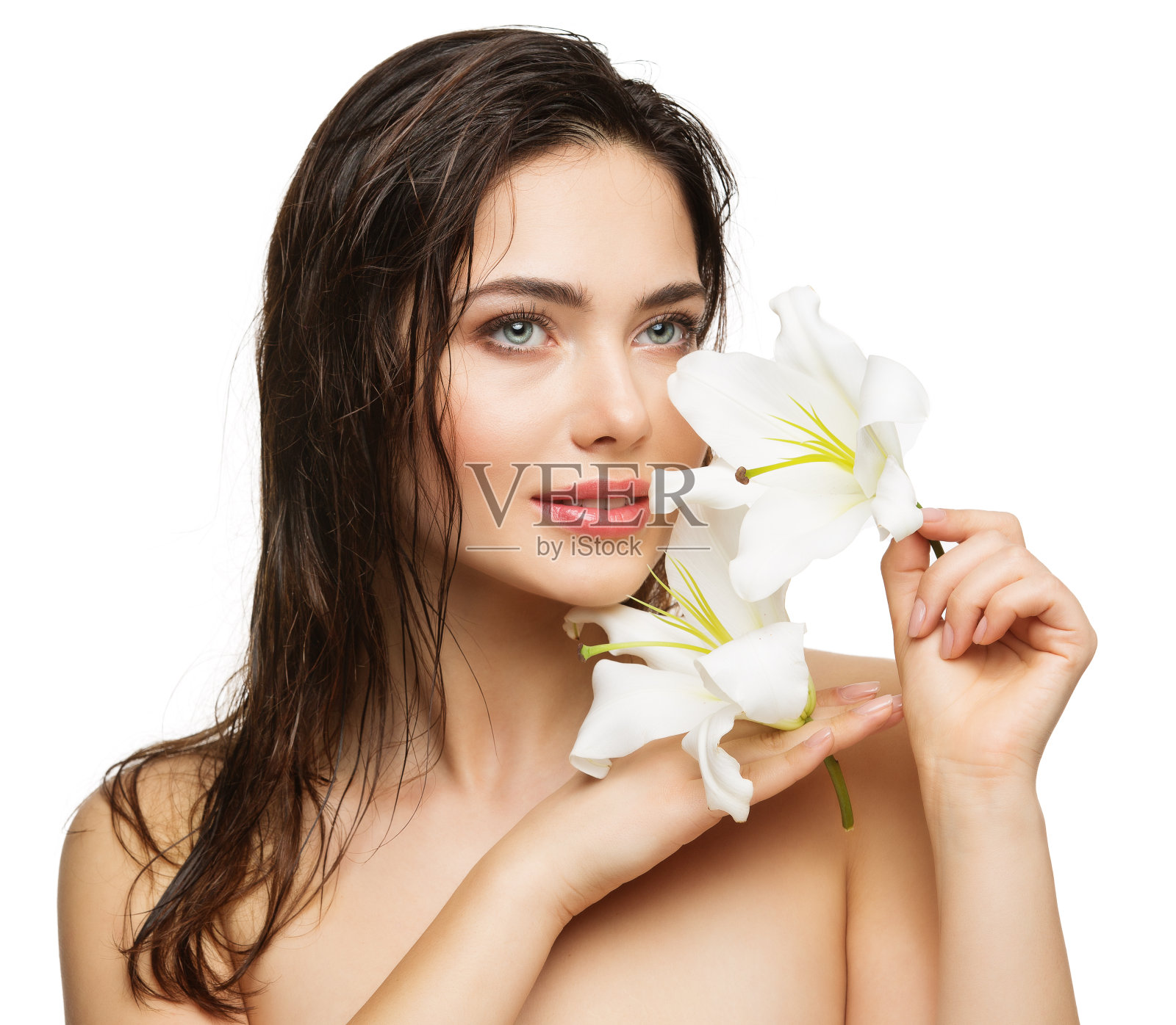 湿发美女模特。面部皮肤护理与健康。年轻的女人与丰满的嘴唇和自然的妆容持有百合花在白色隔离。女性水疗化妆品和美容照片摄影图片