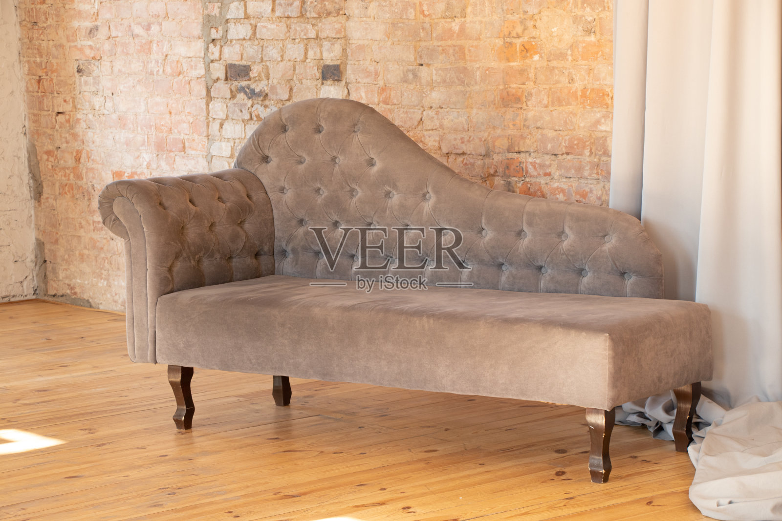灰色的软垫扶手椅抬着砖棕色的墙，在公寓的木地板上，家里有软垫家具，设计精美照片摄影图片