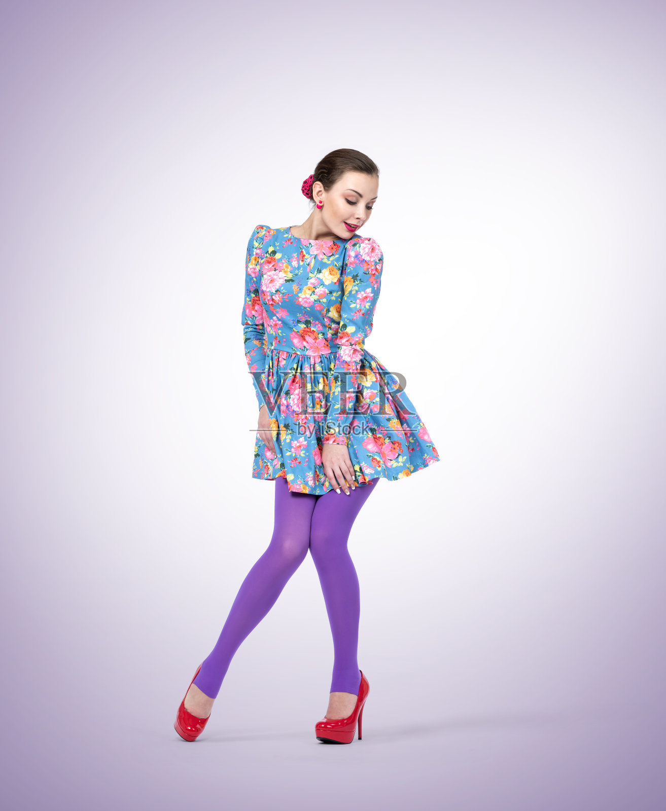 可爱的高个年轻女孩穿着高跟鞋，在浅色背景下穿着裙子摆姿势照片摄影图片