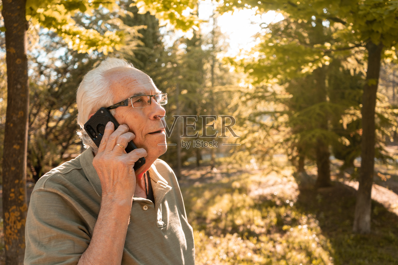 一个阳光明媚的日子，在山上，一个老人用手机打电话的肖像。水平摄影与复制空间。照片摄影图片