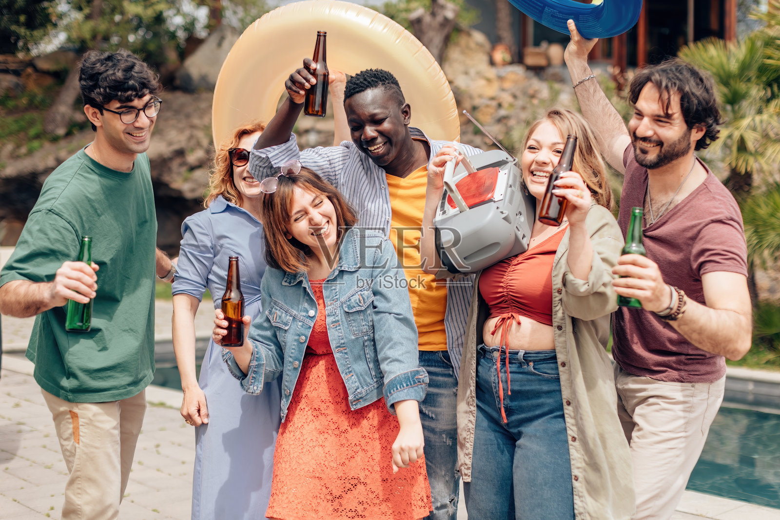 夏天，一群朋友在泳池边欢笑、跳舞、玩乐照片摄影图片