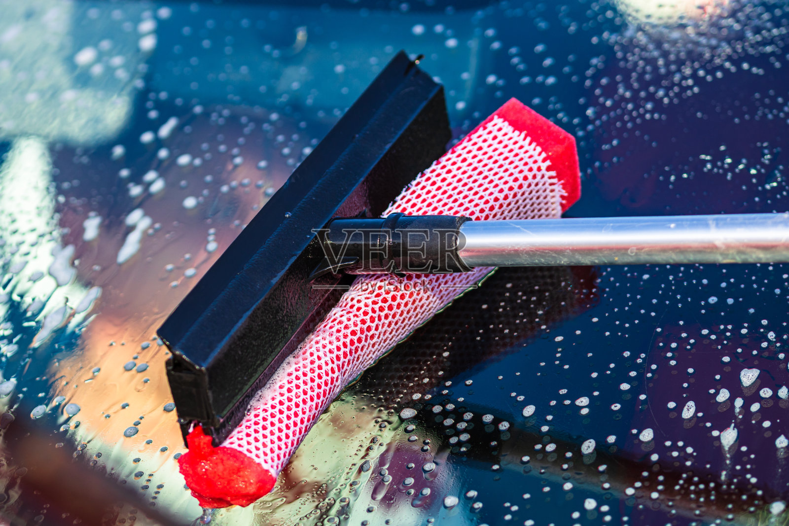 在自助洗车台用拖把清洗汽车前窗，封闭隔离。照片摄影图片