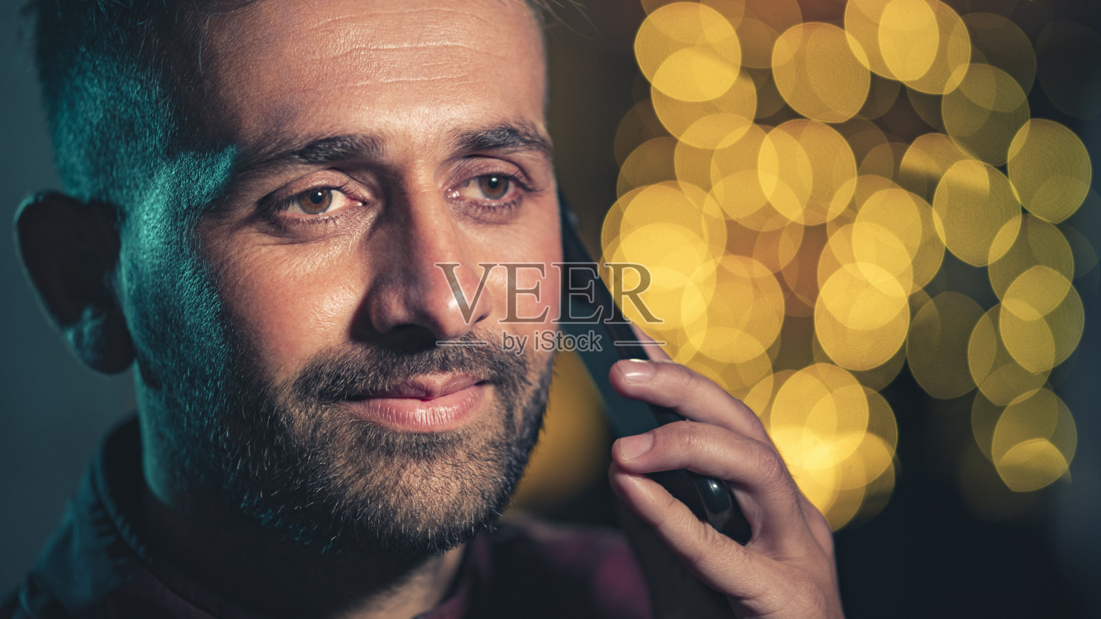 年轻人晚上在城市街道上使用智能手机。照片摄影图片