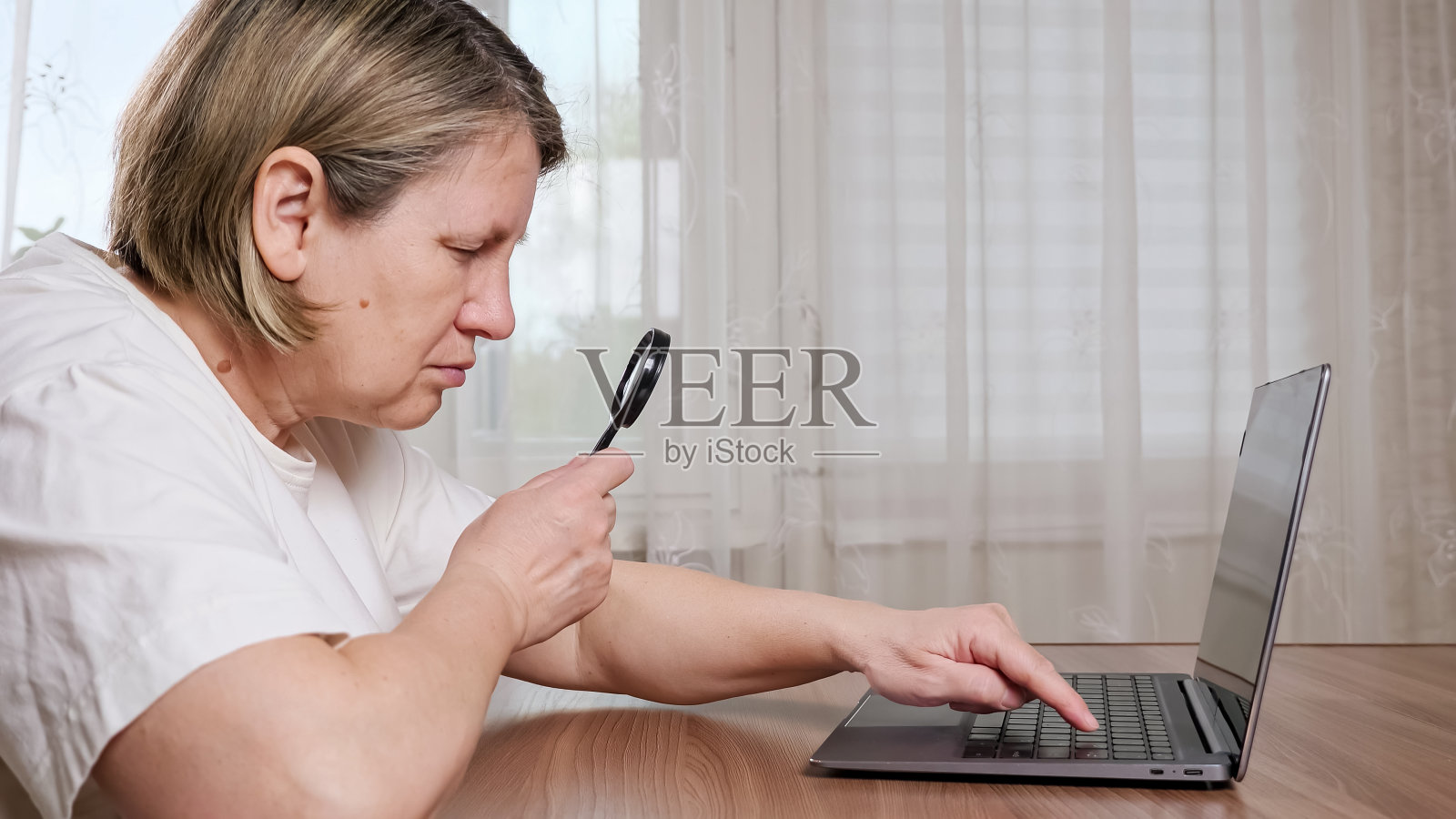 老妇人用放大镜在键盘上打字照片摄影图片