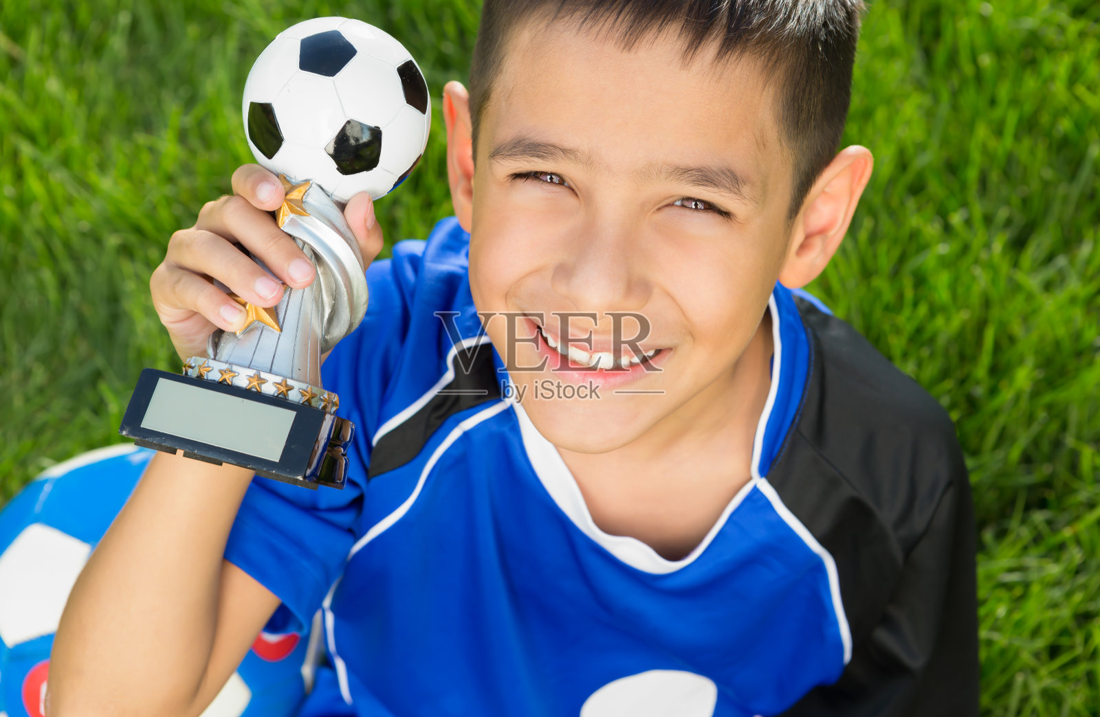 小男孩足球运动员拿着奖杯照片摄影图片