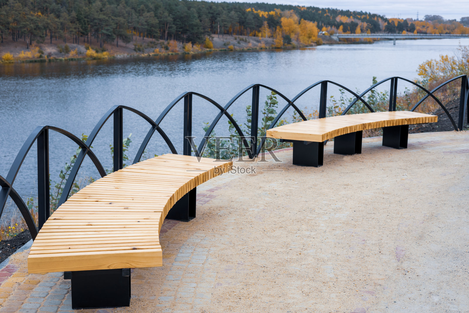 金属栅栏旁的半圆形长椅，秋季的木质座椅照片摄影图片