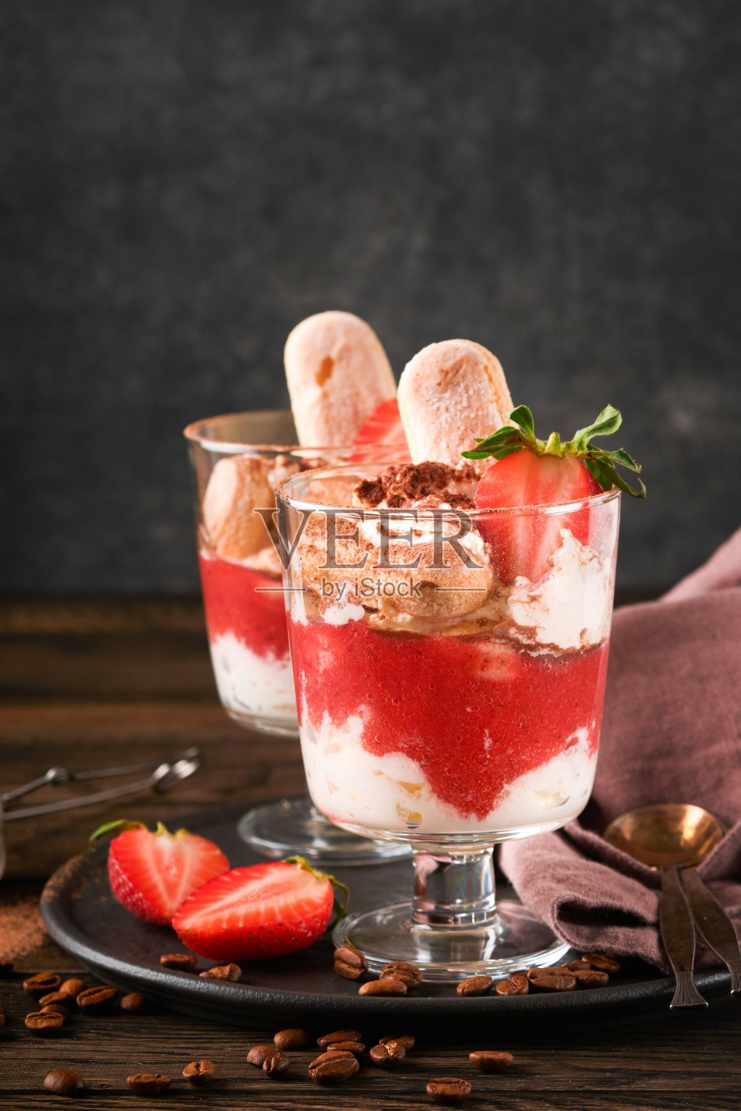草莓提拉米苏。传统的意大利甜点提拉米苏在玻璃新鲜草莓和薄荷叶在旧的木制黑暗的桌子背景。副本的空间。食品的背景。照片摄影图片