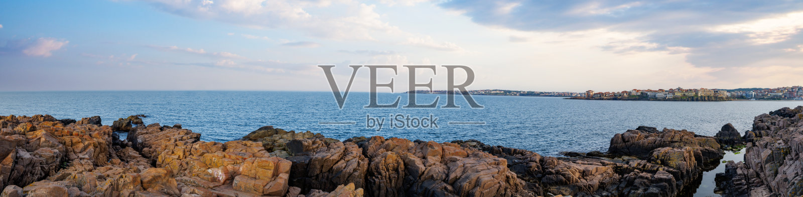 黑海附近的鹅卵石海滩全景，映衬着蓝天和远处的城镇照片摄影图片