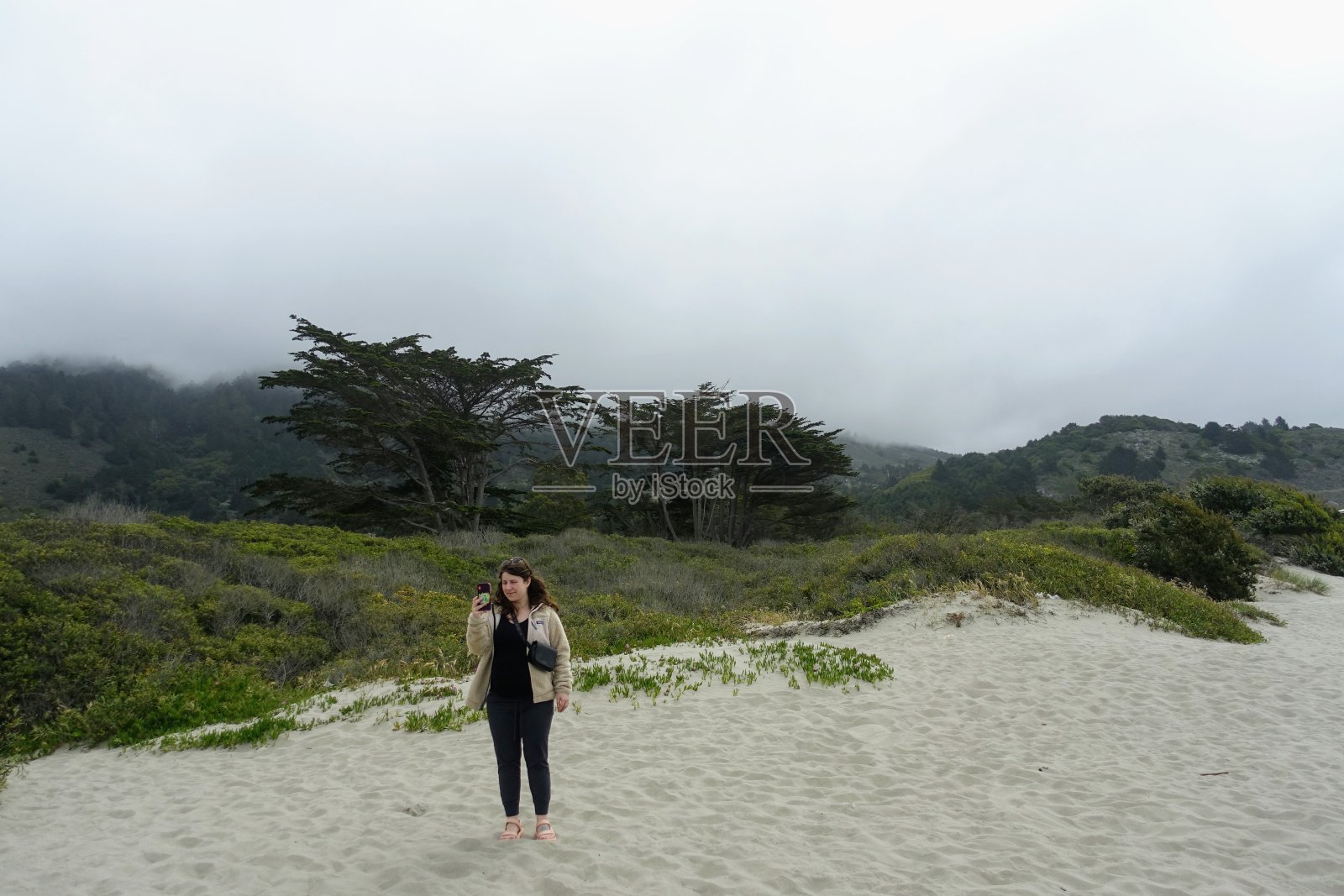 一个雾蒙蒙的早晨，在美国北加州的斯廷森海滩，一个年轻的女人欣赏着沿着加利福尼亚海岸无尽的海滩和海洋的美丽景色照片摄影图片