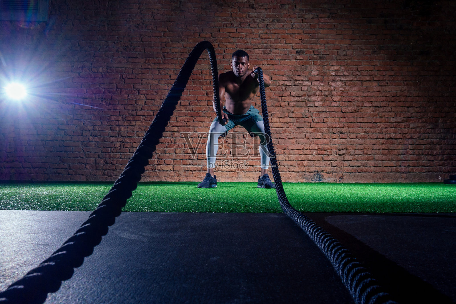 在体育馆里，多民族运动员裸露着性感的胸部，用战绳锻炼身体照片摄影图片