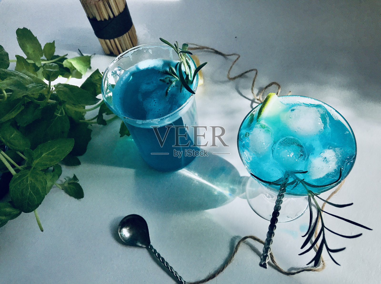 蓝色冷饮在一个有冰块的杯子上白色的桌子蓝色的背景。照片摄影图片