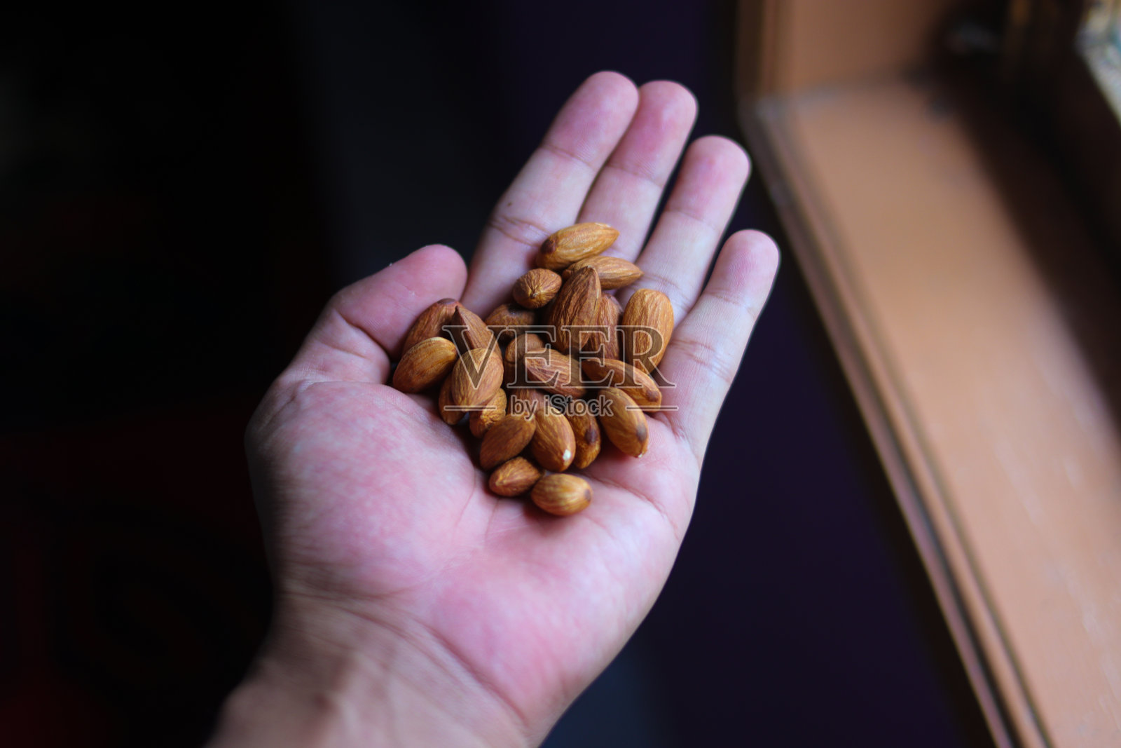 手里拿着一堆杏仁。照片摄影图片