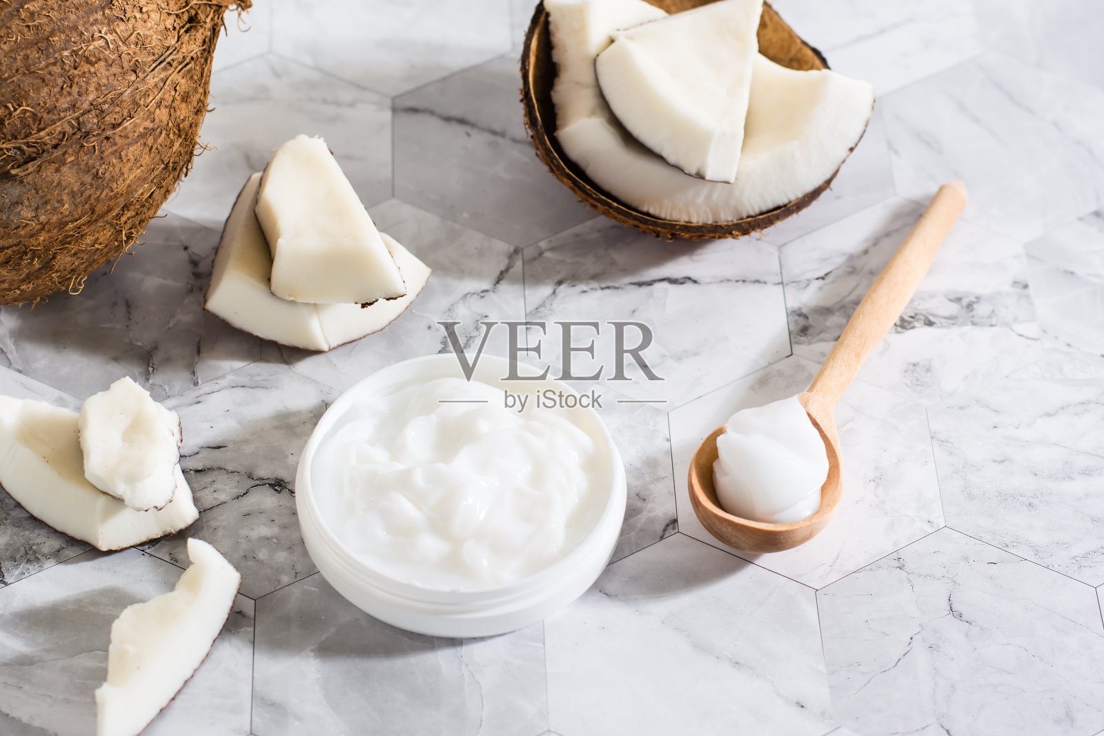 新鲜的椰子油装在罐子里，木勺和椰子放在桌子上。天然的化妆品照片摄影图片