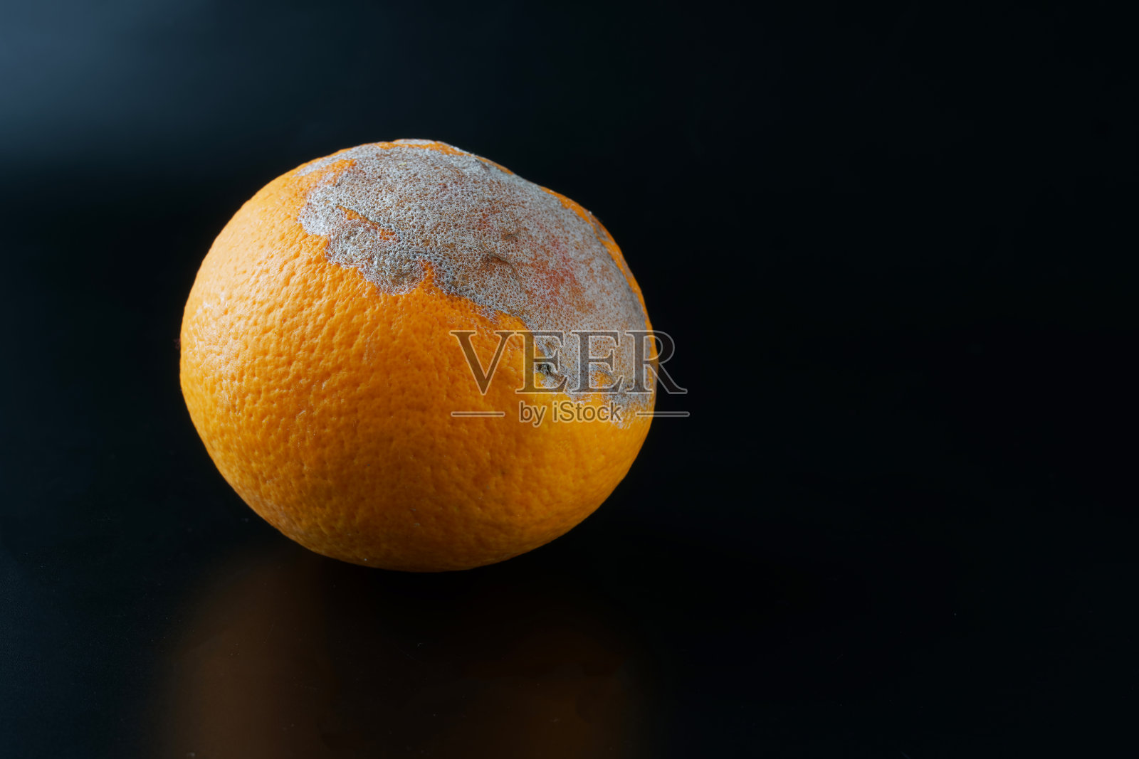 在黑色渐变背景上的干燥的腐烂的老橙子。食品和水果变质的概念问题照片摄影图片