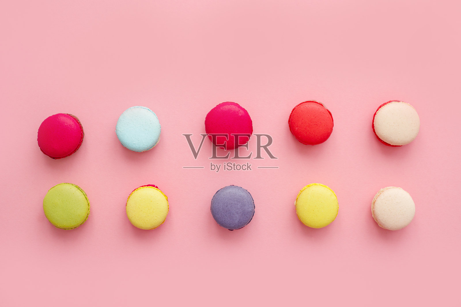 彩色的法式马卡龙或马卡龙在粉红色的背景，甜点。照片摄影图片