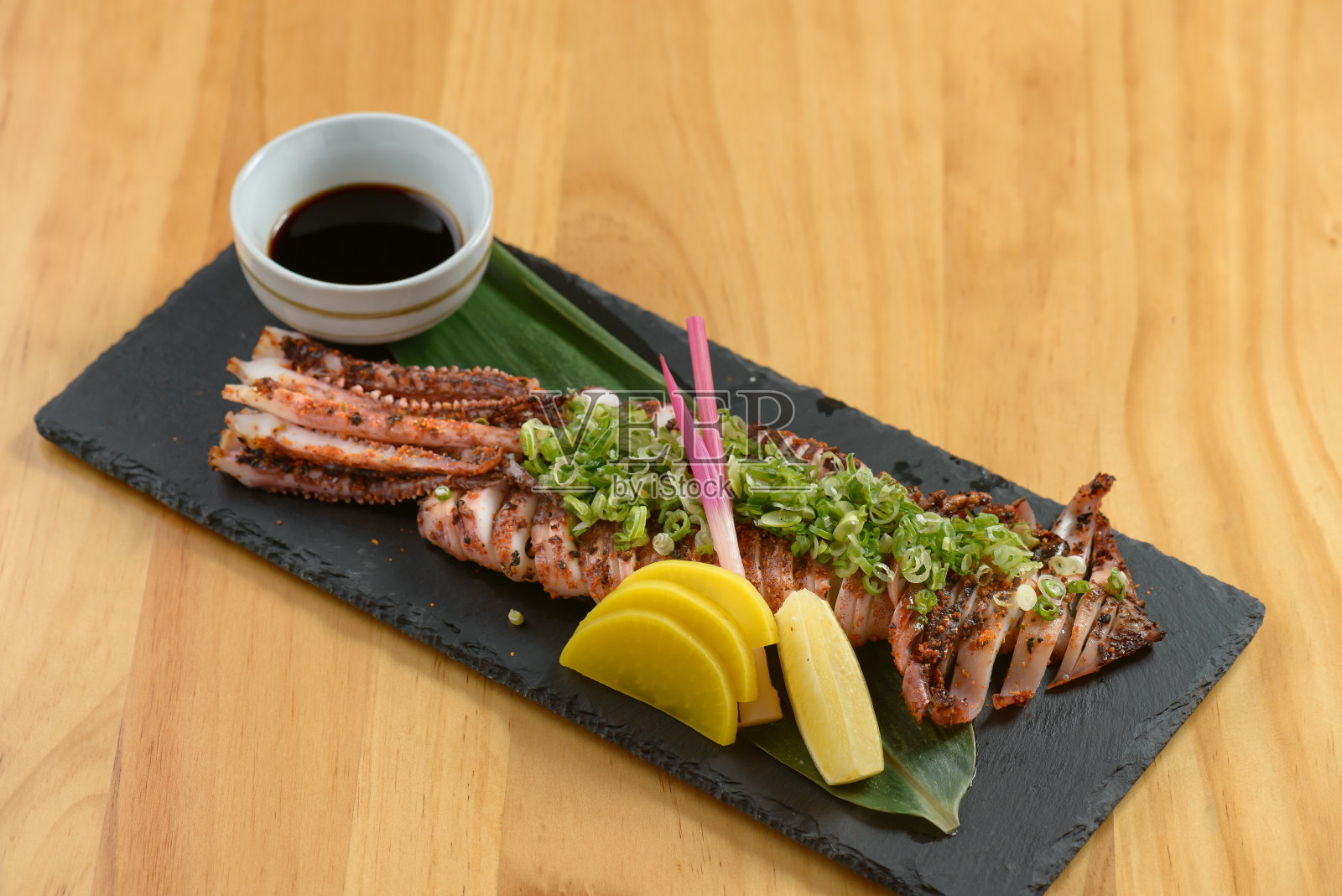 日本食物烤牛肉干与柠檬和酱油在一个黑色的盘子孤立在木制桌子上俯瞰照片摄影图片