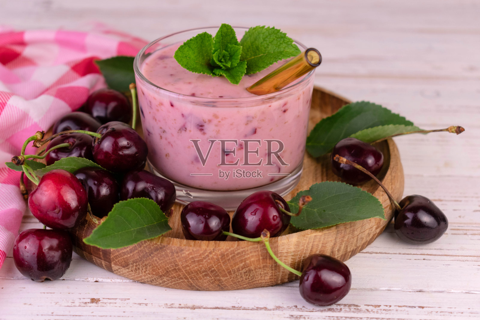 新鲜的樱桃冰沙在一个木制托盘的杯子。照片摄影图片