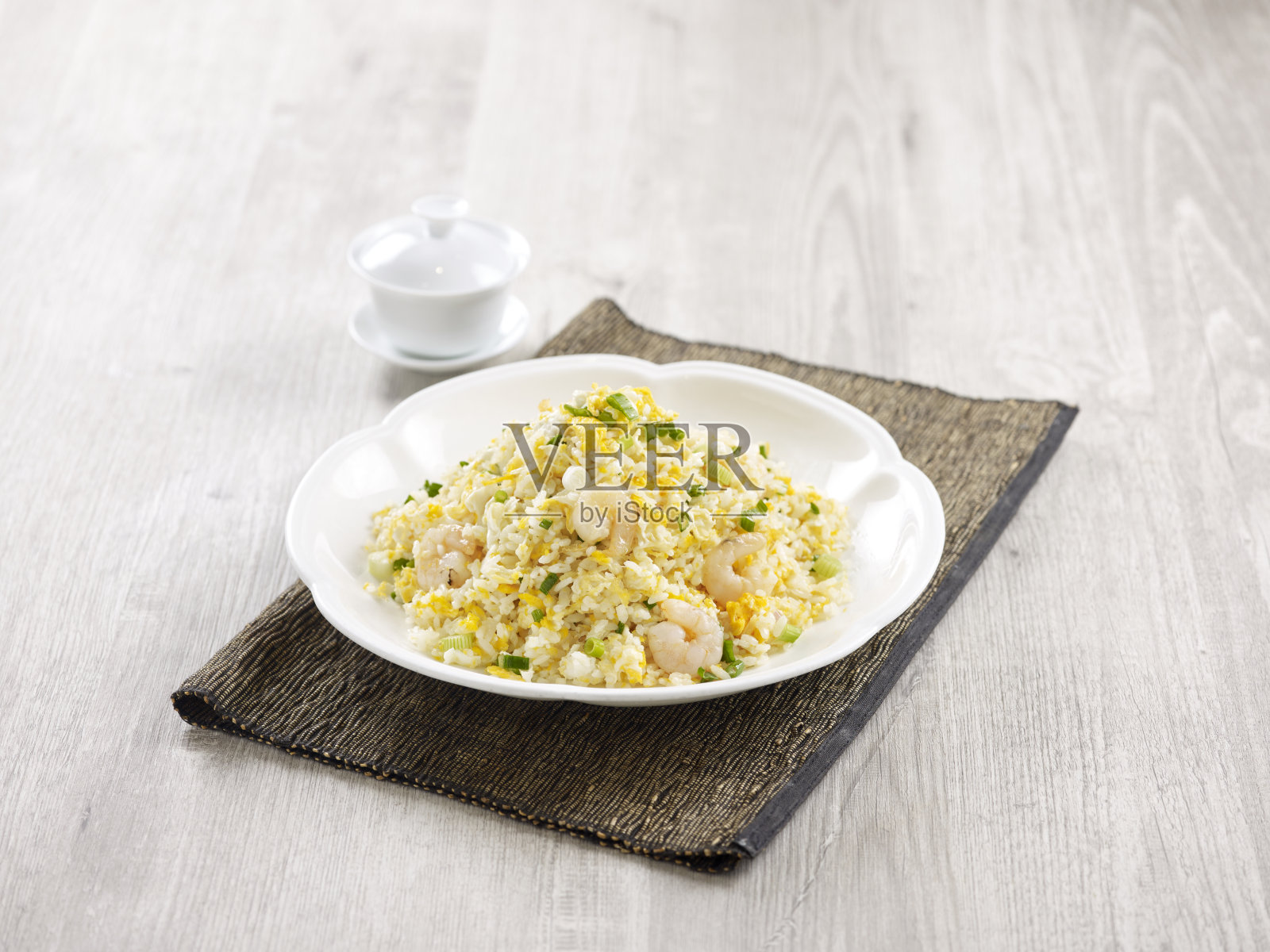 虾炒饭用筷子夹在盘子里孤立在垫子上的侧视图在灰色的背景上照片摄影图片