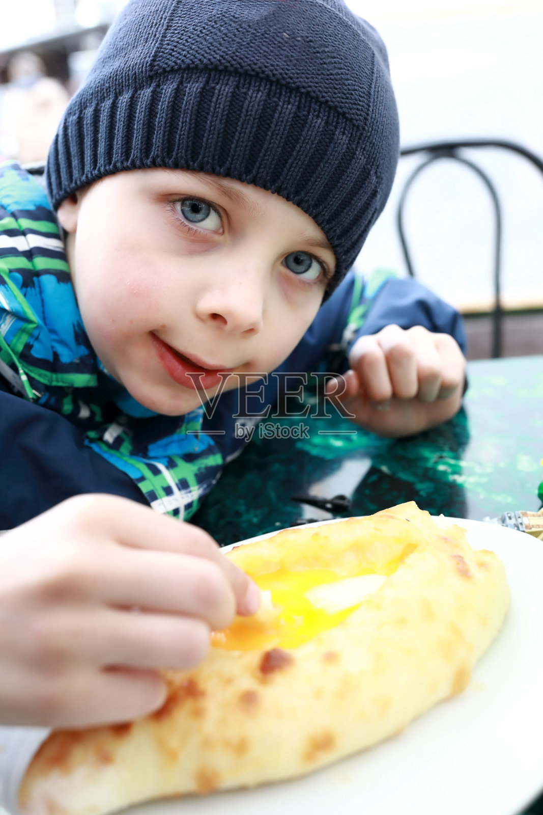男孩把一块阿扎里亚哈切布里蘸到蛋黄里照片摄影图片