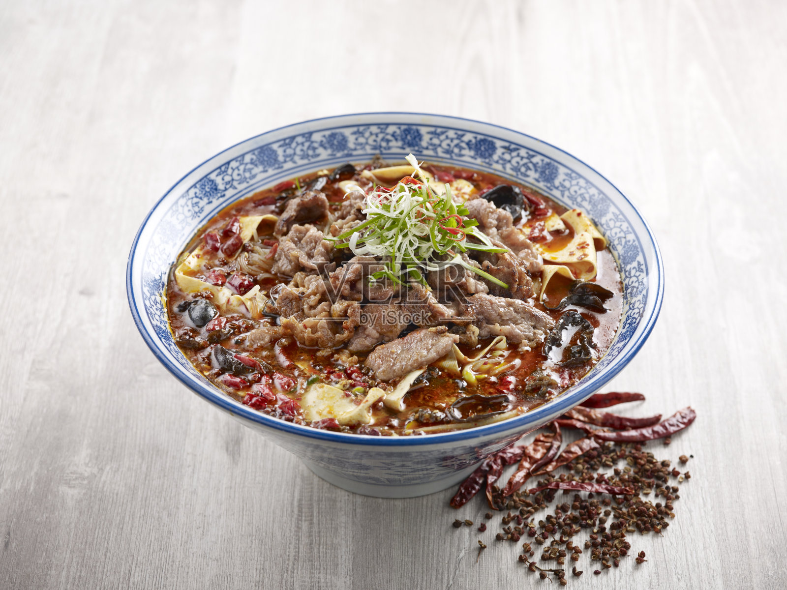 水煮大理石纹牛肉在四川风格与筷子服务在一个盘子孤立席侧视图在灰色的背景照片摄影图片