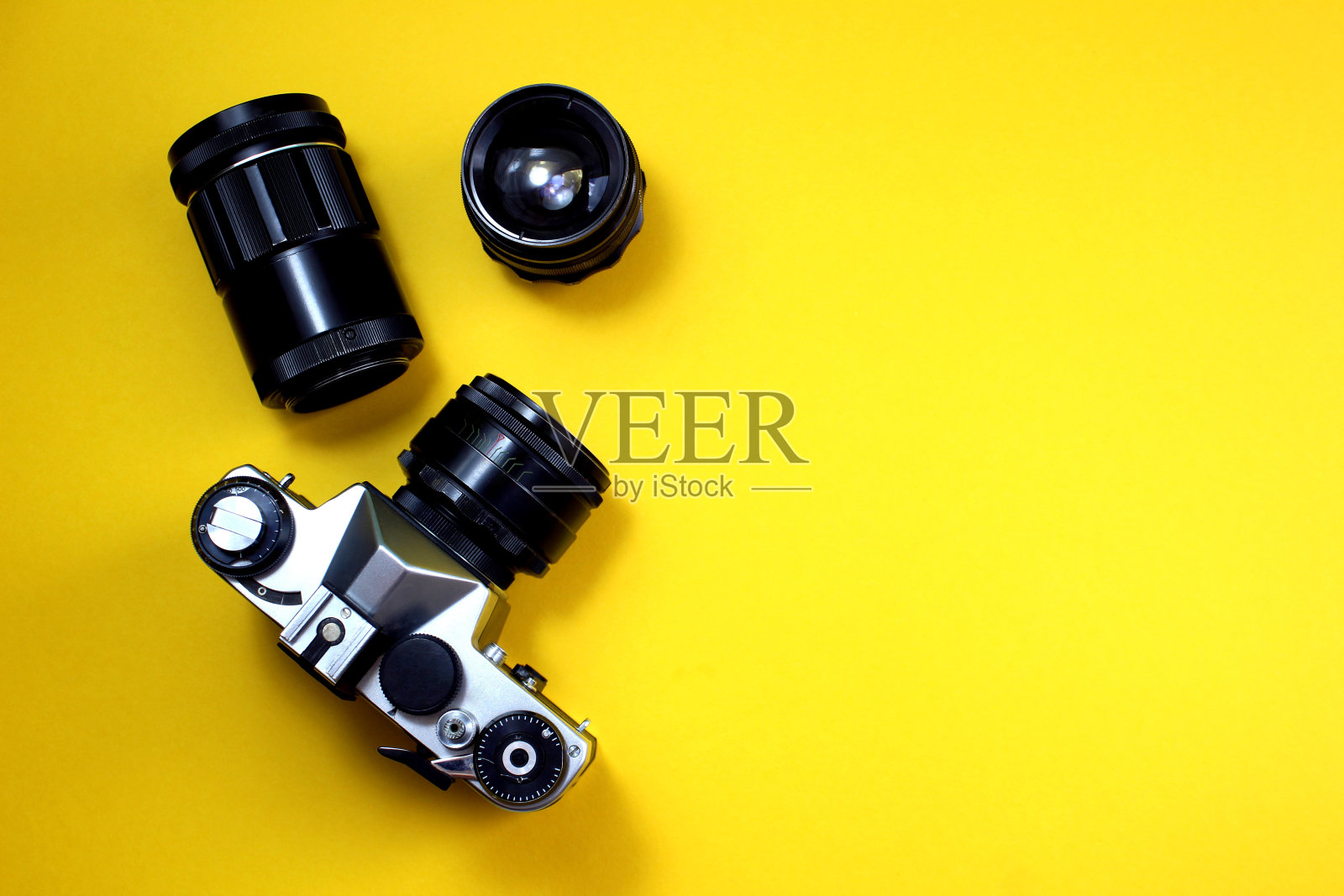 黄色背景上的复古黑色相机有不同的镜头。照片摄影图片