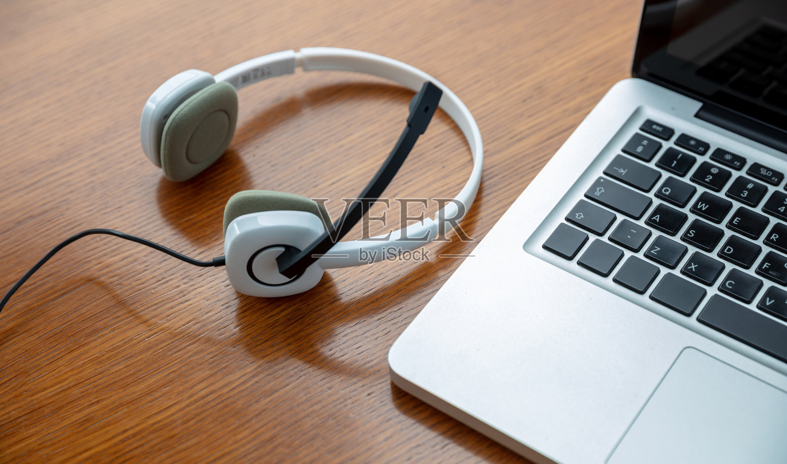 家庭办公室，耳机放在笔记本电脑上，木桌上。呼叫中心，客户支持，帮助台照片摄影图片