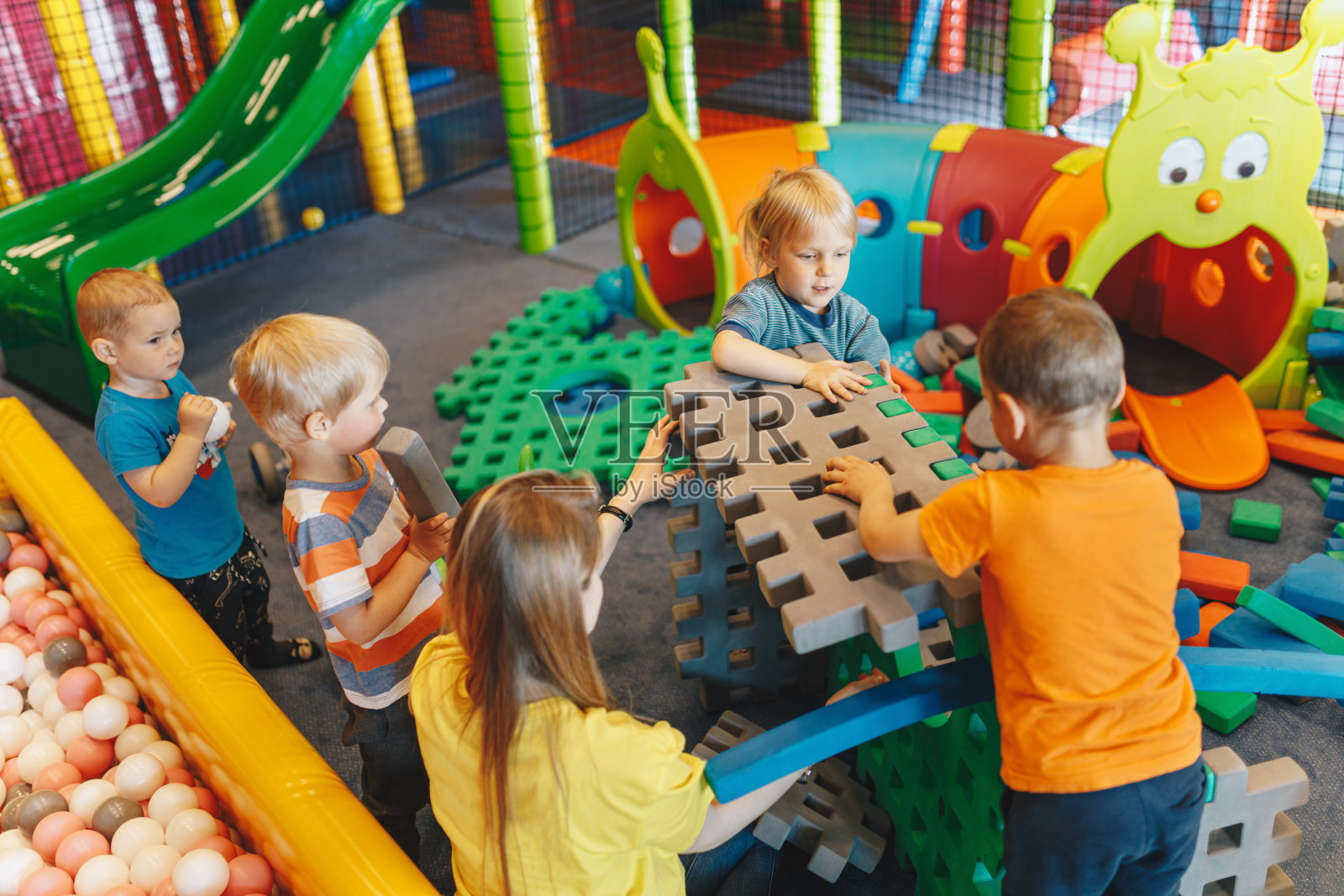 幼儿园的教育小组活动。快乐的孩子玩泡沫块与年轻的老师保姆照片摄影图片