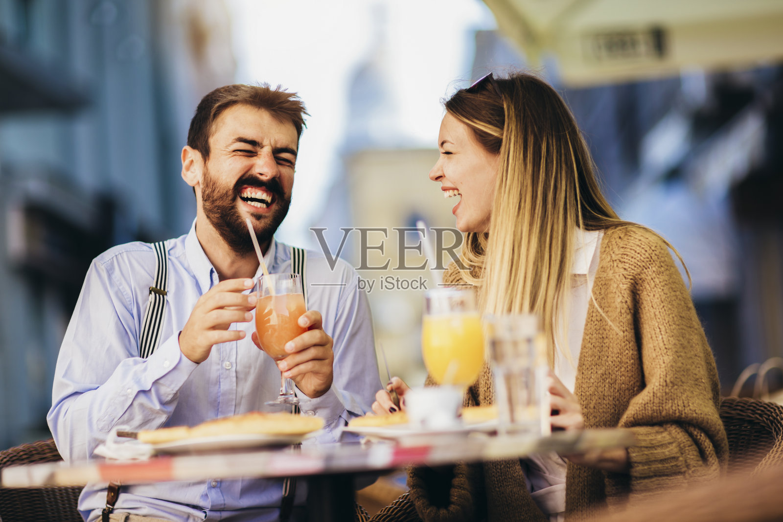一对年轻夫妇坐在餐厅的户外吃披萨。照片摄影图片