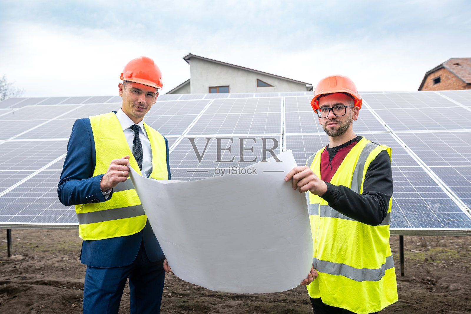 穿着工作服的高大男子正在考虑是否在户外安装太阳能电池板。照片摄影图片