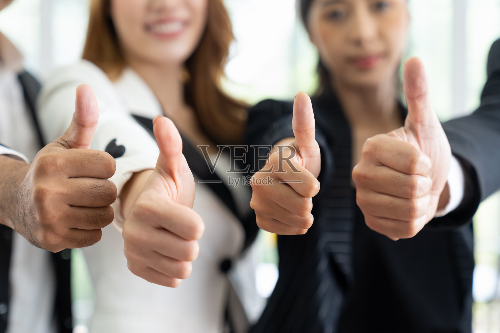 商务人士在办公室开会时竖起大拇指的特写。一群不同的商人分享商业战略计划的成功。照片摄影图片