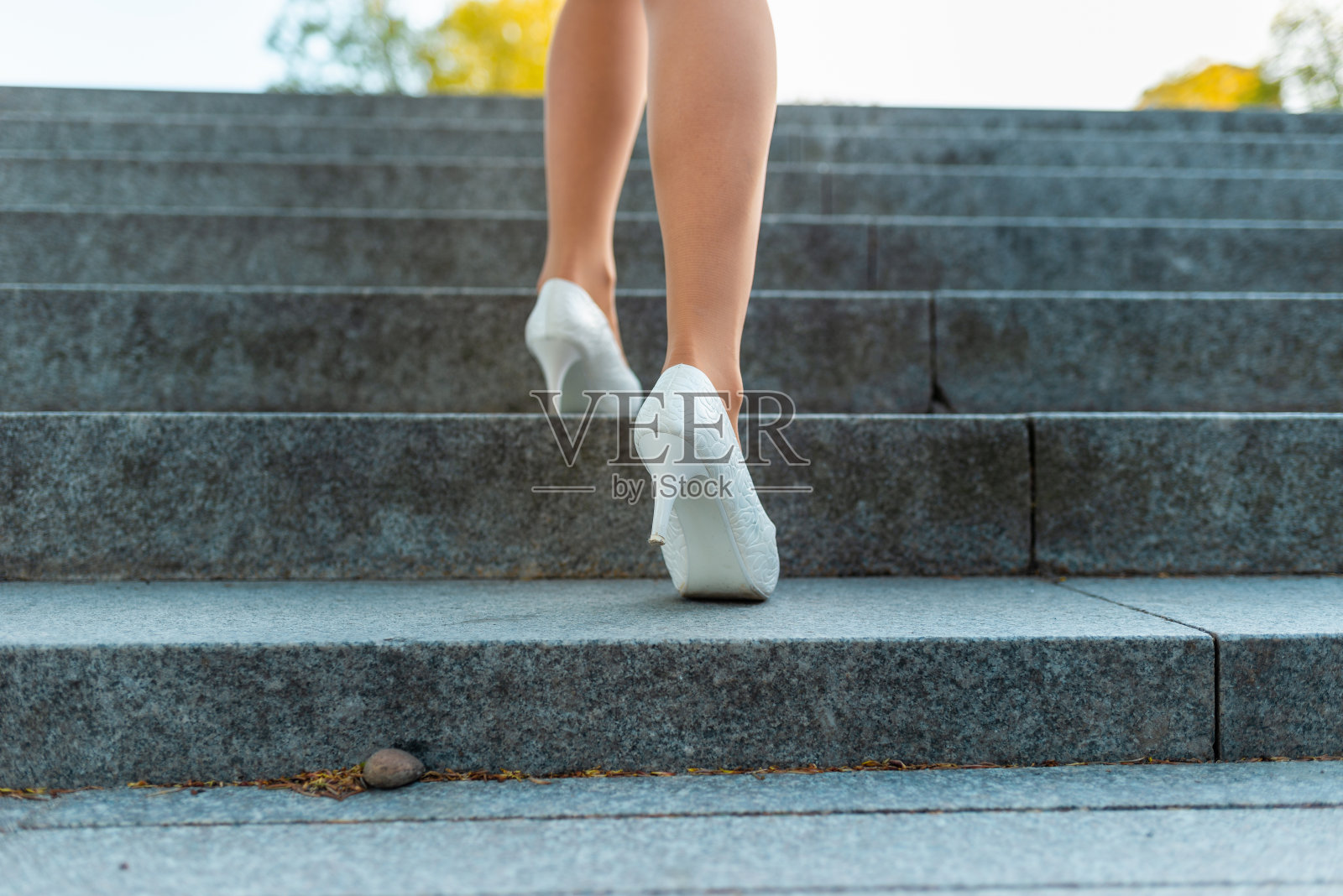 可爱的商业女性的腿走在城市街道的楼梯上。照片摄影图片