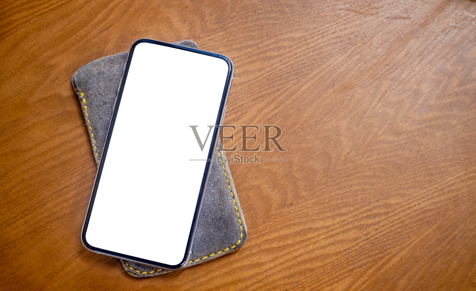 在木制桌子上的皮革外壳上模拟手机照片摄影图片