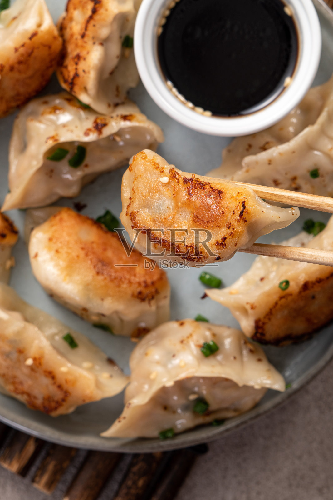 平底锅煎的饺子饺子在一个盘子酱油在灰色的桌子背景。照片摄影图片