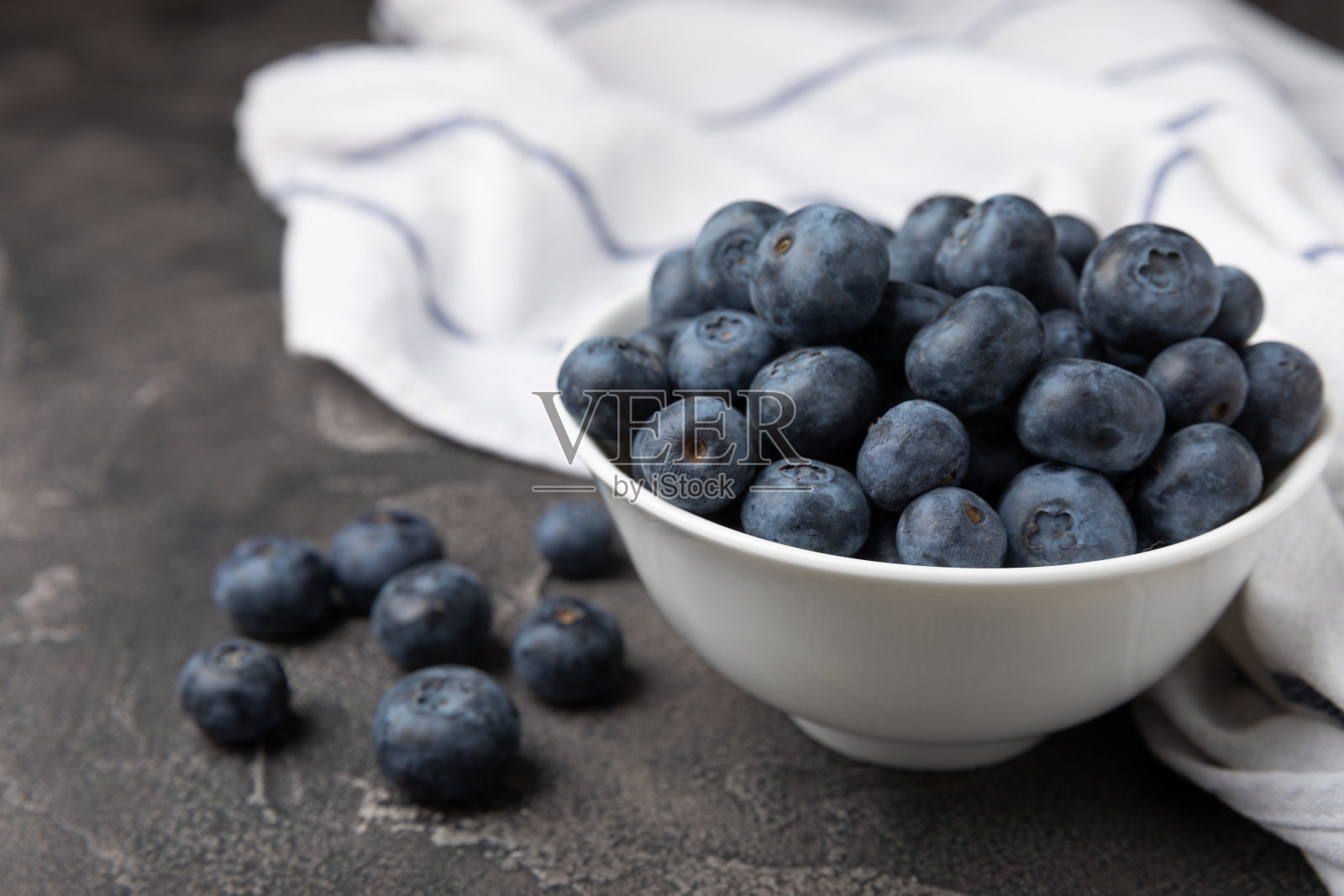 蓝莓在陶瓷碗上黑色的纹理背景。成熟新鲜的蓝莓。维生素。健康食品。多汁的浆果。副本的空间。文本的地方照片摄影图片